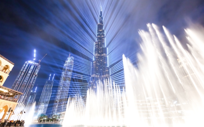 Dubai Fountain show with Burj Khalifa illuminated at night.