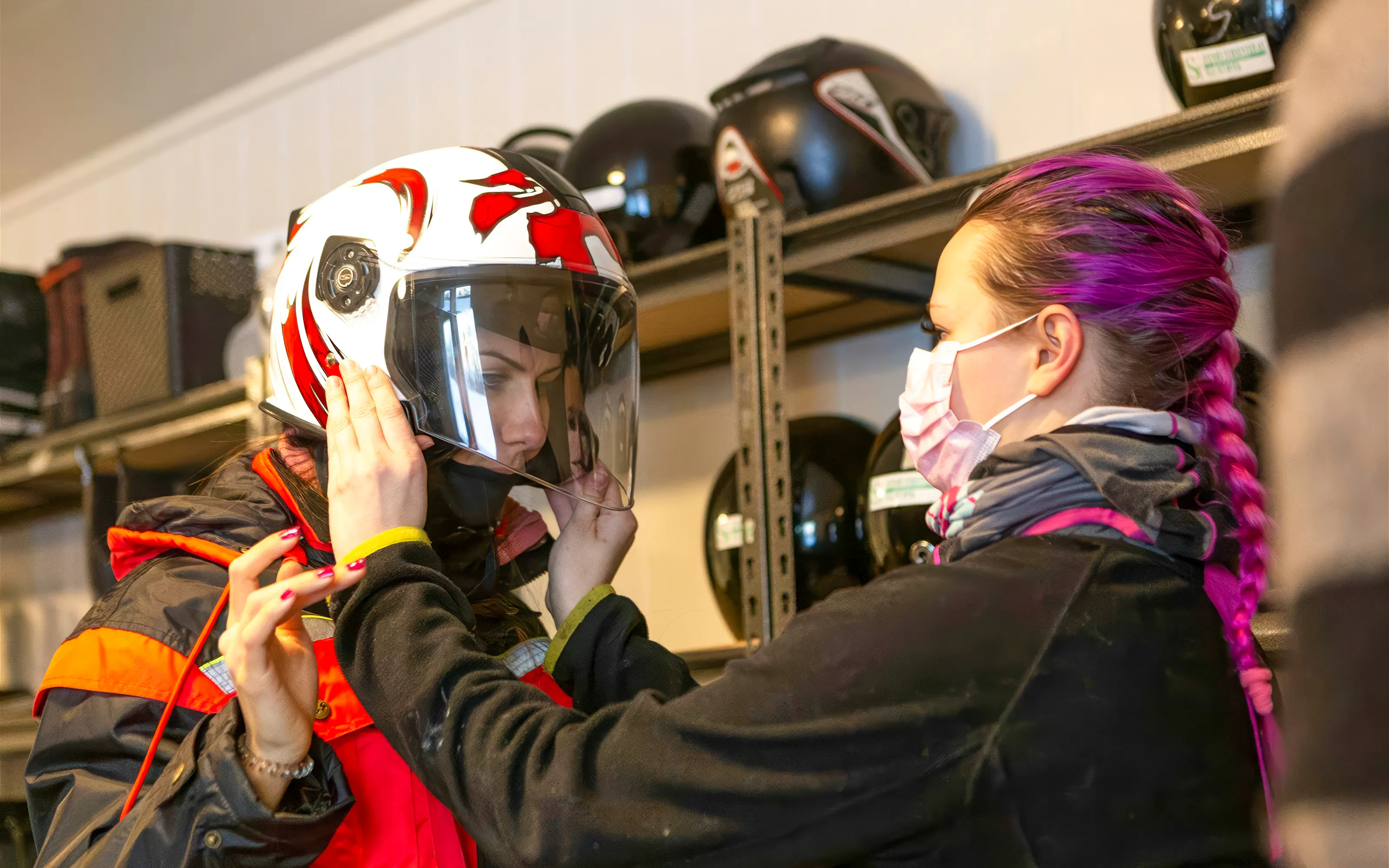 Guest preparing for a snowmobile ride in Tromsø with helmet fitting assistance.
