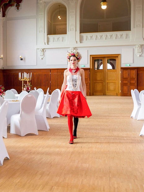 Hungarian Royal Guard exhibition hall with elegantly set tables and a performer in traditional attire.