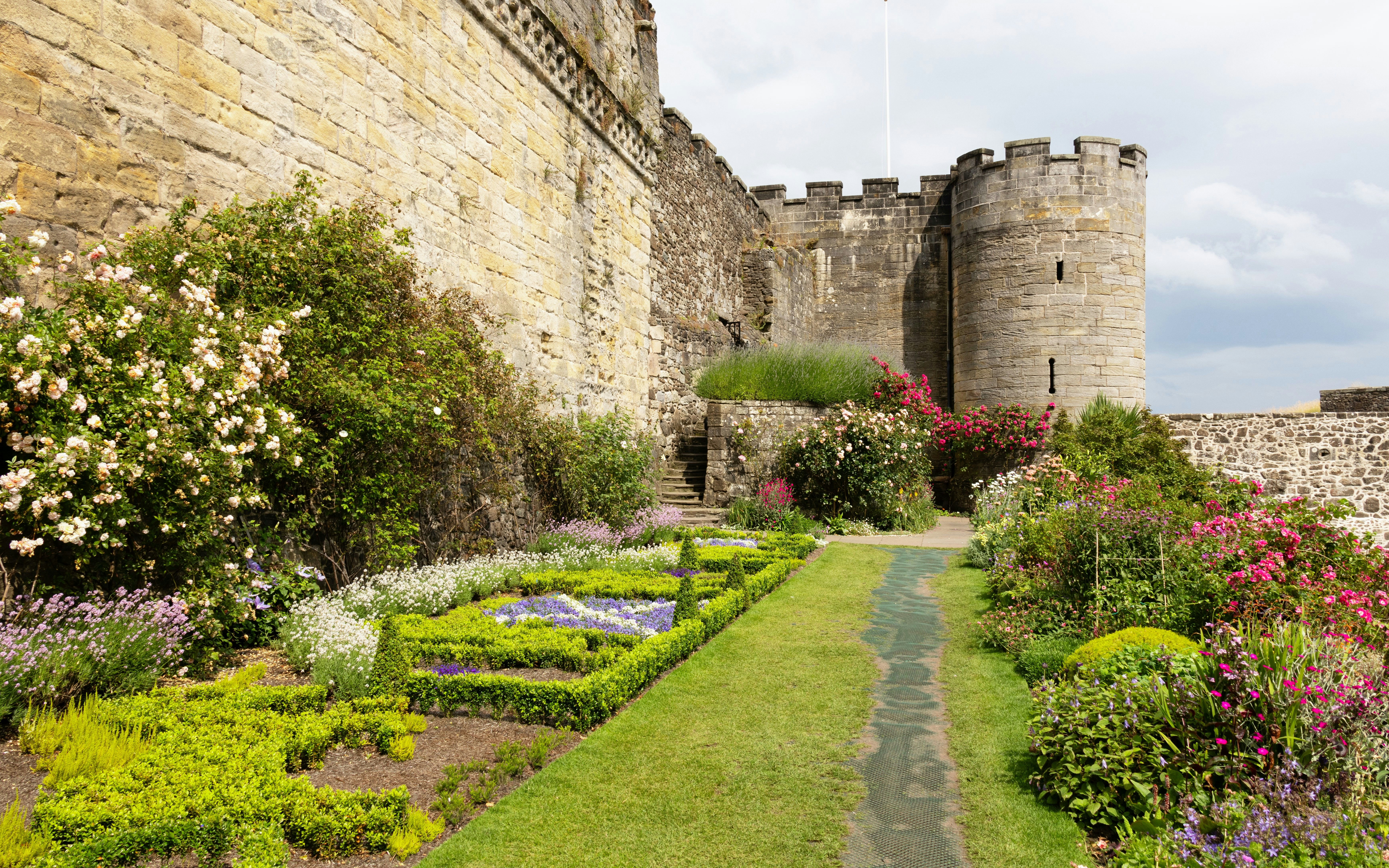 Gardens along the stone walls of Stirling Castle, Scotland, with colorful flowers and greenery.