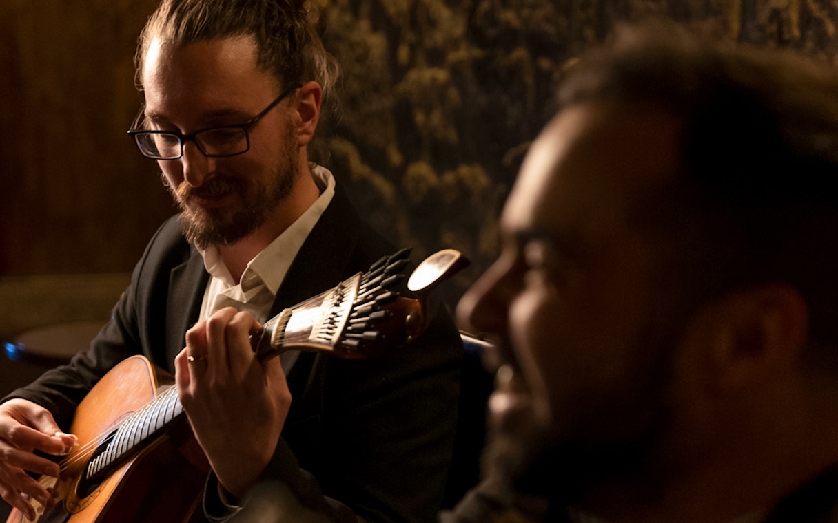 Musician playing guitar at Fado Maior during an intimate Fado show.