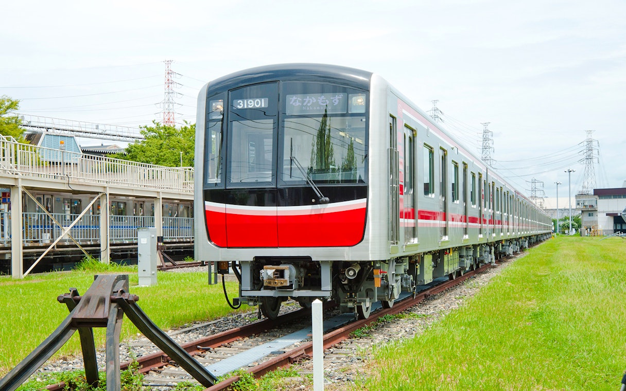 Kansai Railway train on tracks in a green landscape, Japan.