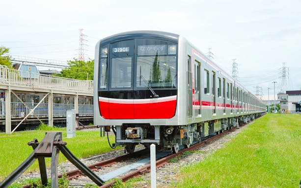 Kansai Railway train on tracks in a green landscape, Japan.