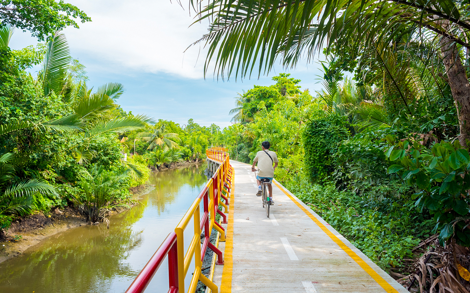 Young man cycling through lush greenery in Bang Krachao, Thailand.
