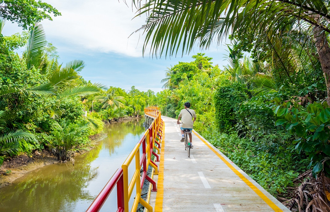 Young man cycling through lush greenery in Bang Krachao, Thailand.