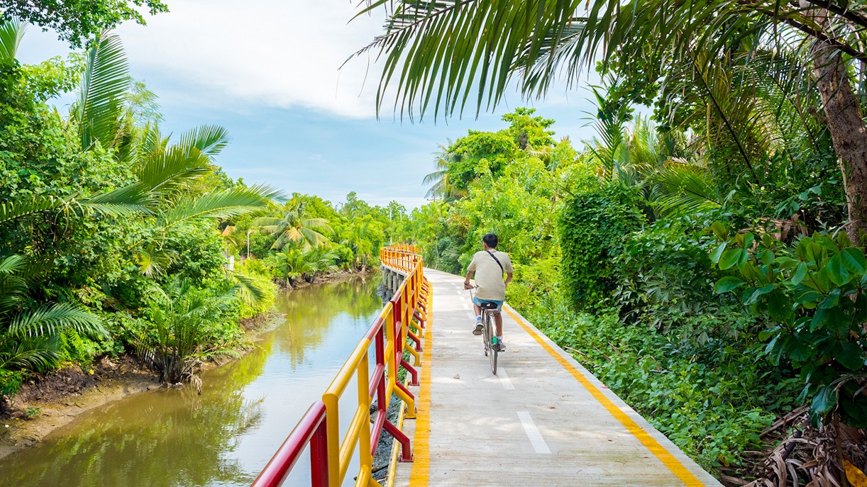 Young man cycling through lush greenery in Bang Krachao, Thailand.