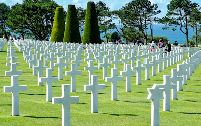Visitors walking among white crosses at Normandy American Cemetery near Omaha Beach.