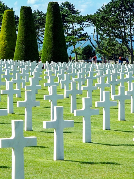 Visitors walking among white crosses at Normandy American Cemetery near Omaha Beach.