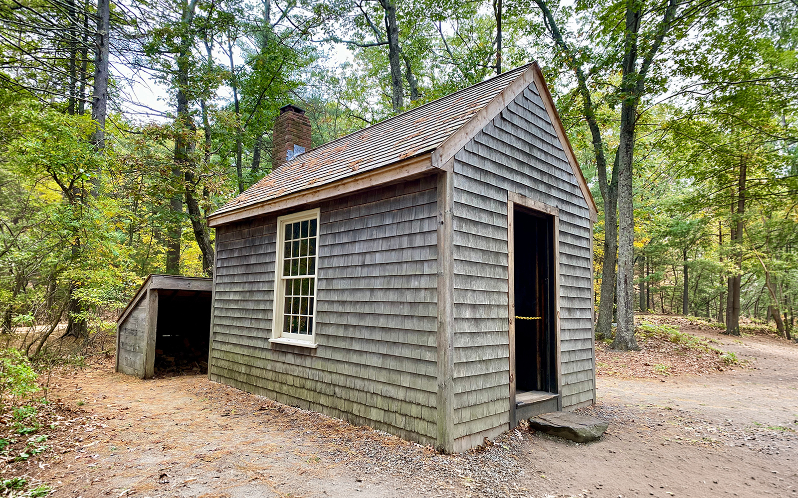 Replica of Thoreau's cabin at Walden Pond, Concord, MA, surrounded by trees.
