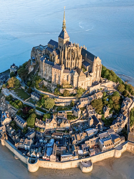 Aerial view of Mont Saint Michel surrounded by water and sand in Normandy, France.