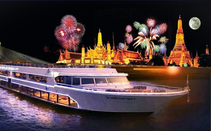 River cruise near illuminated Wat Arun with fireworks in Bangkok, Thailand.
