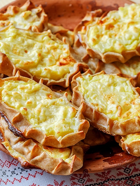 Traditional Finnish Karelian pies on a wooden plate, served on a patterned cloth.