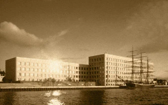 Historic ship docked by modern building in Copenhagen Royal District.