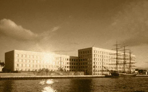 Historic ship docked by modern building in Copenhagen Royal District.