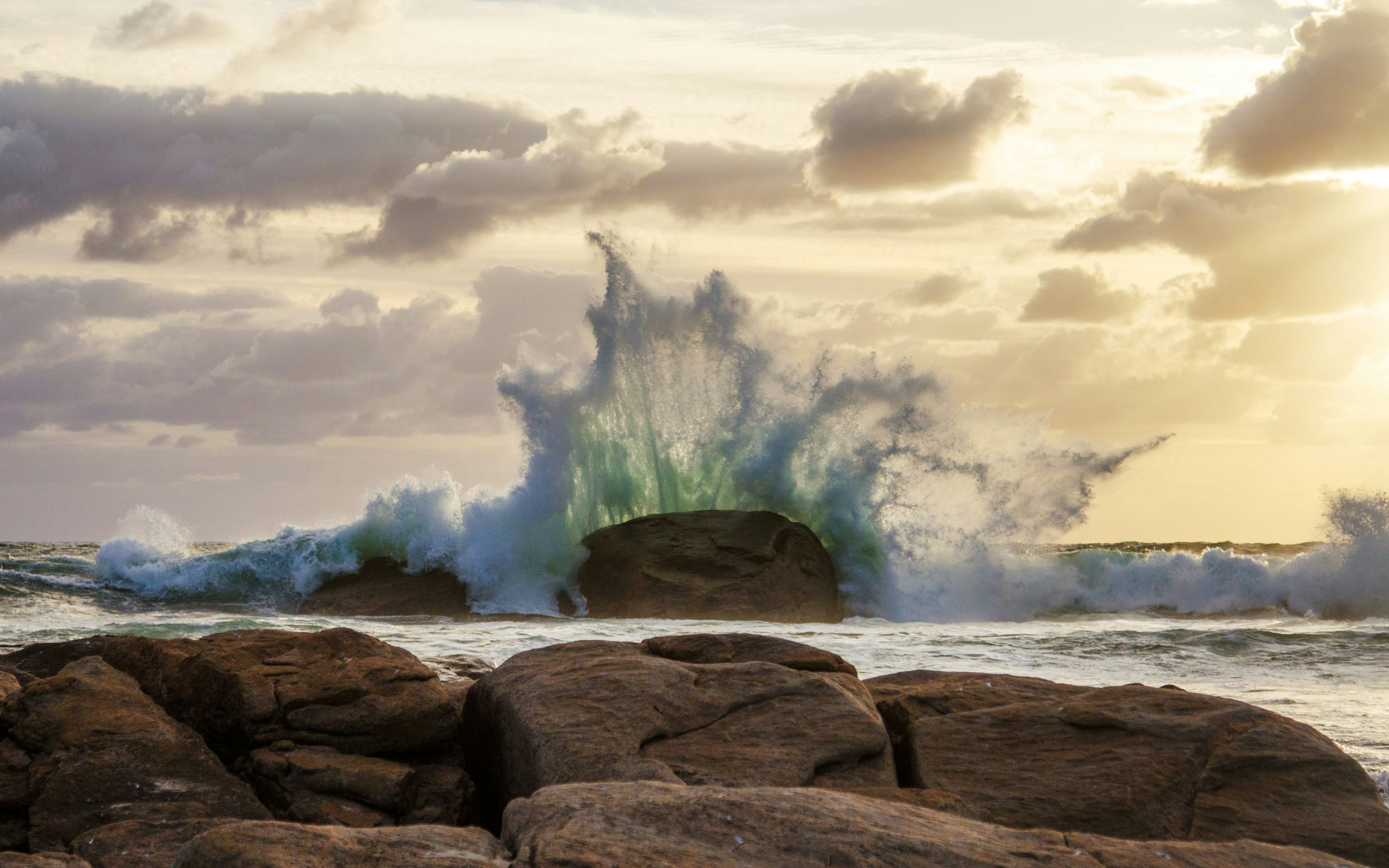 Waves crashing against rocks at Redgate Beach during sunset.