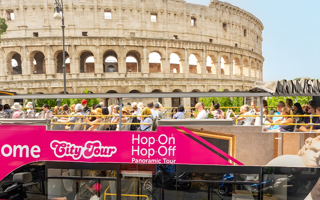 Open-top bus tour passing by the Colosseum in Rome.