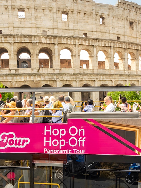 Open-top bus tour passing by the Colosseum in Rome.