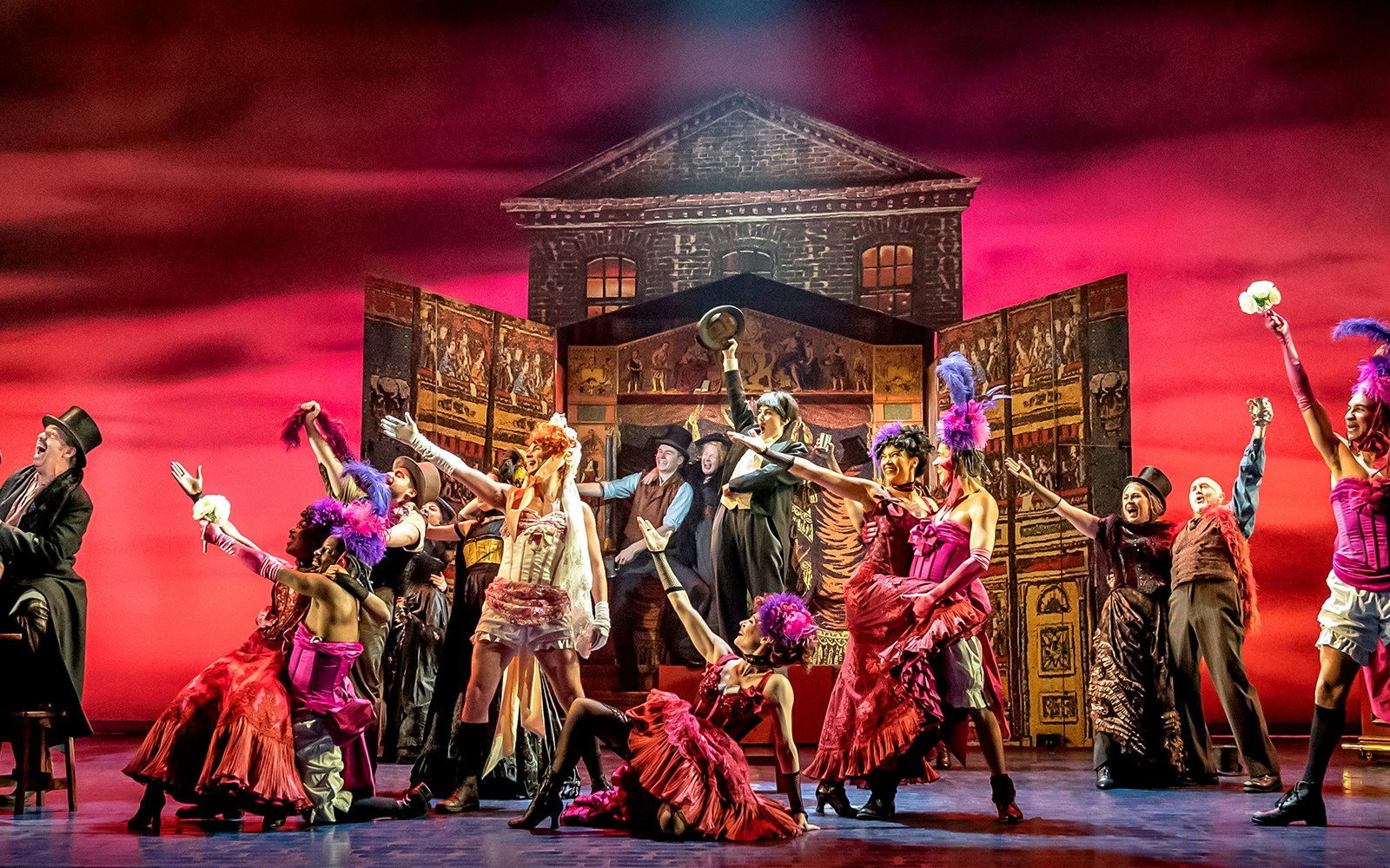 Stage performance of "My Fair Lady" with actors in vibrant costumes and a lively backdrop.