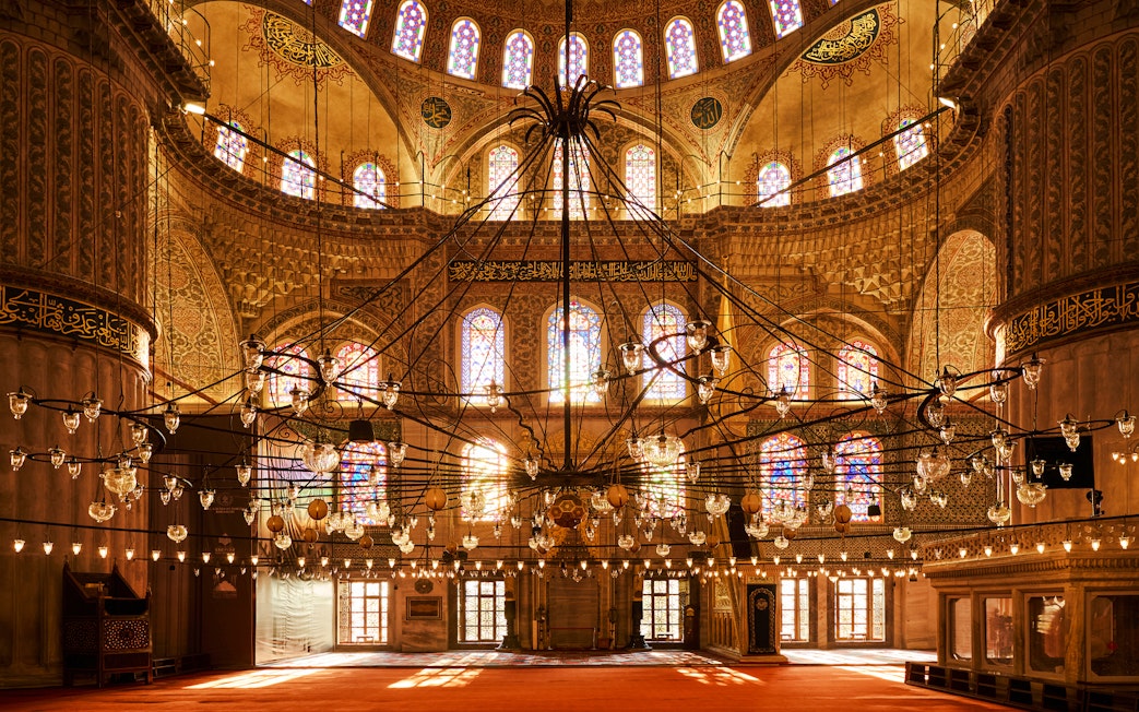 Interior view of Blue Mosque with ornate chandeliers and stained glass windows, Istanbul, Turkey.
