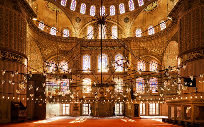 Interior view of Blue Mosque with ornate chandeliers and stained glass windows, Istanbul, Turkey.