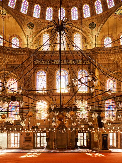 Interior view of Blue Mosque with ornate chandeliers and stained glass windows, Istanbul, Turkey.