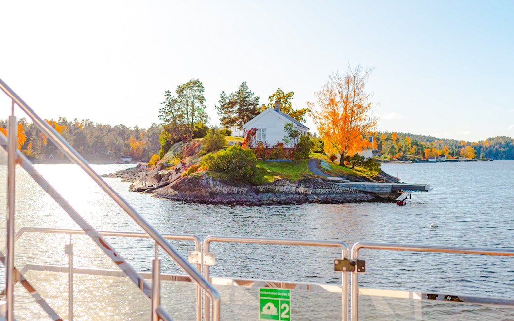 Fjord view from a boat with a small island and house near Oslo during a sightseeing cruise.