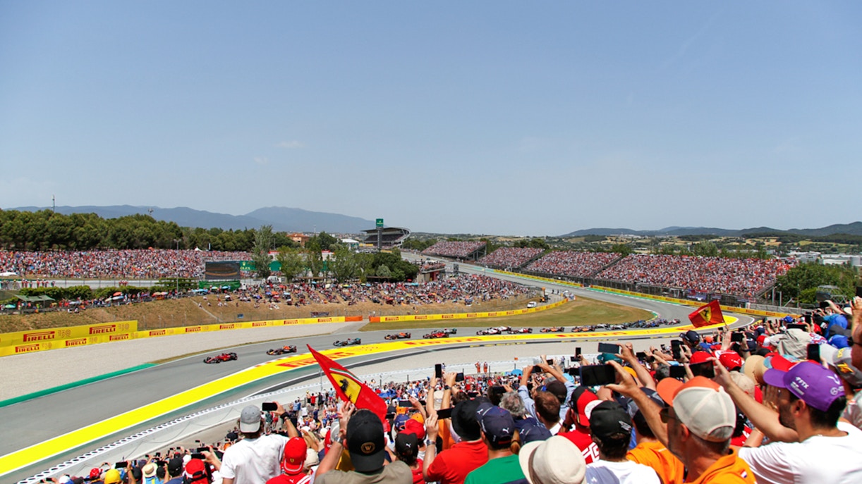 Barcelona Formula 1 race view from grandstands with cars on track and spectators in the stands.