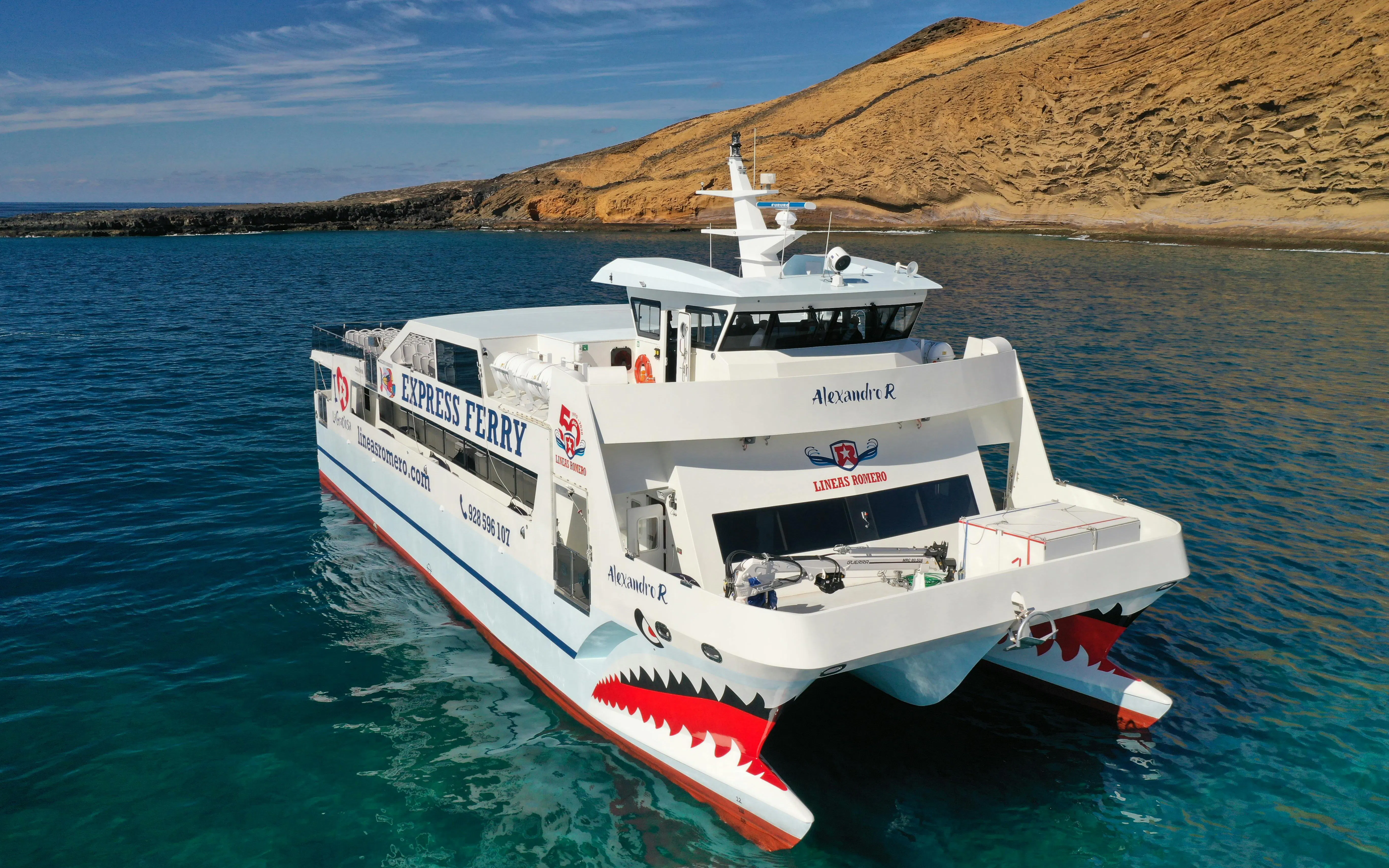 Ferry approaching La Graciosa Island with rocky coastline in the background.
