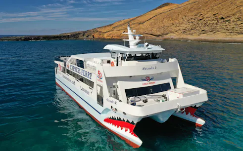 Ferry approaching La Graciosa Island with rocky coastline in the background.