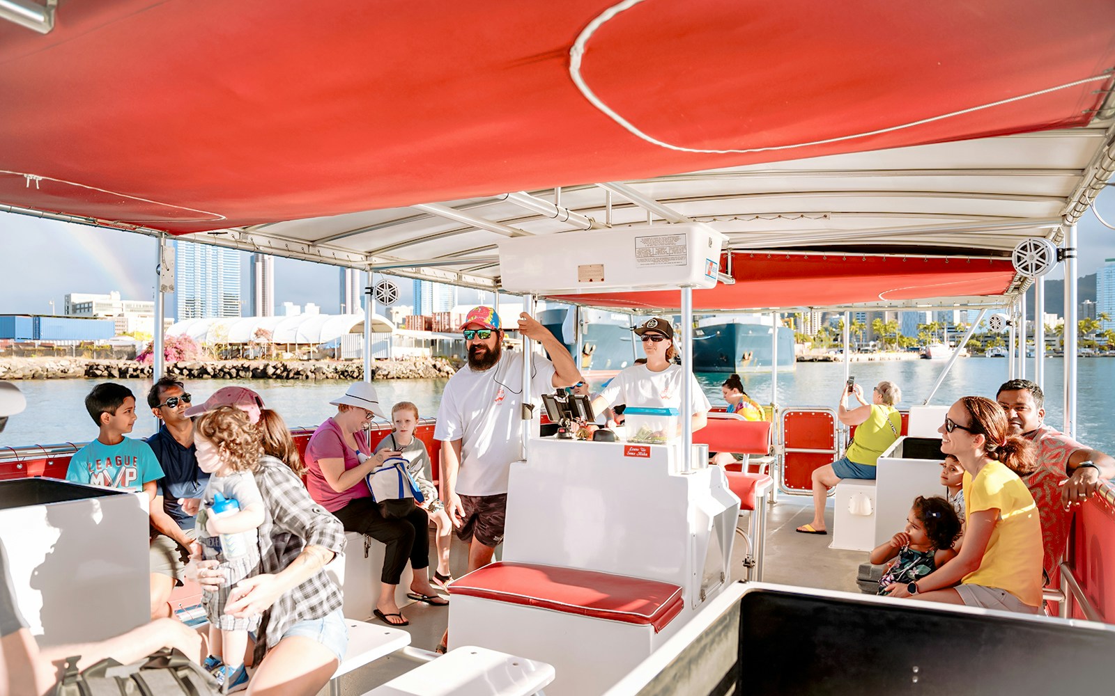 Passengers enjoying a Hawaii glass-bottom boat tour with city skyline in the background.