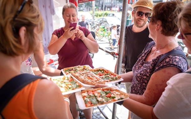 Tour group enjoying pizza on a guided food tour in Kreuzberg.
