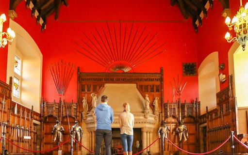 Visitors observing the Great Hall's medieval armor display inside Edinburgh Castle.