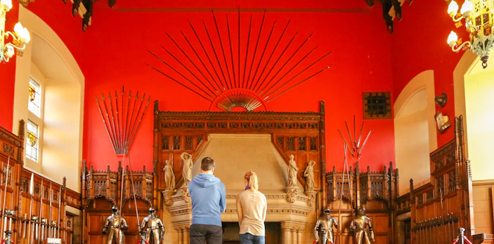 Visitors observing the Great Hall's medieval armor display inside Edinburgh Castle.