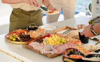 Sydney Harbour Cruise meal with assorted meats, cheeses, fruits, and crackers at sunset.