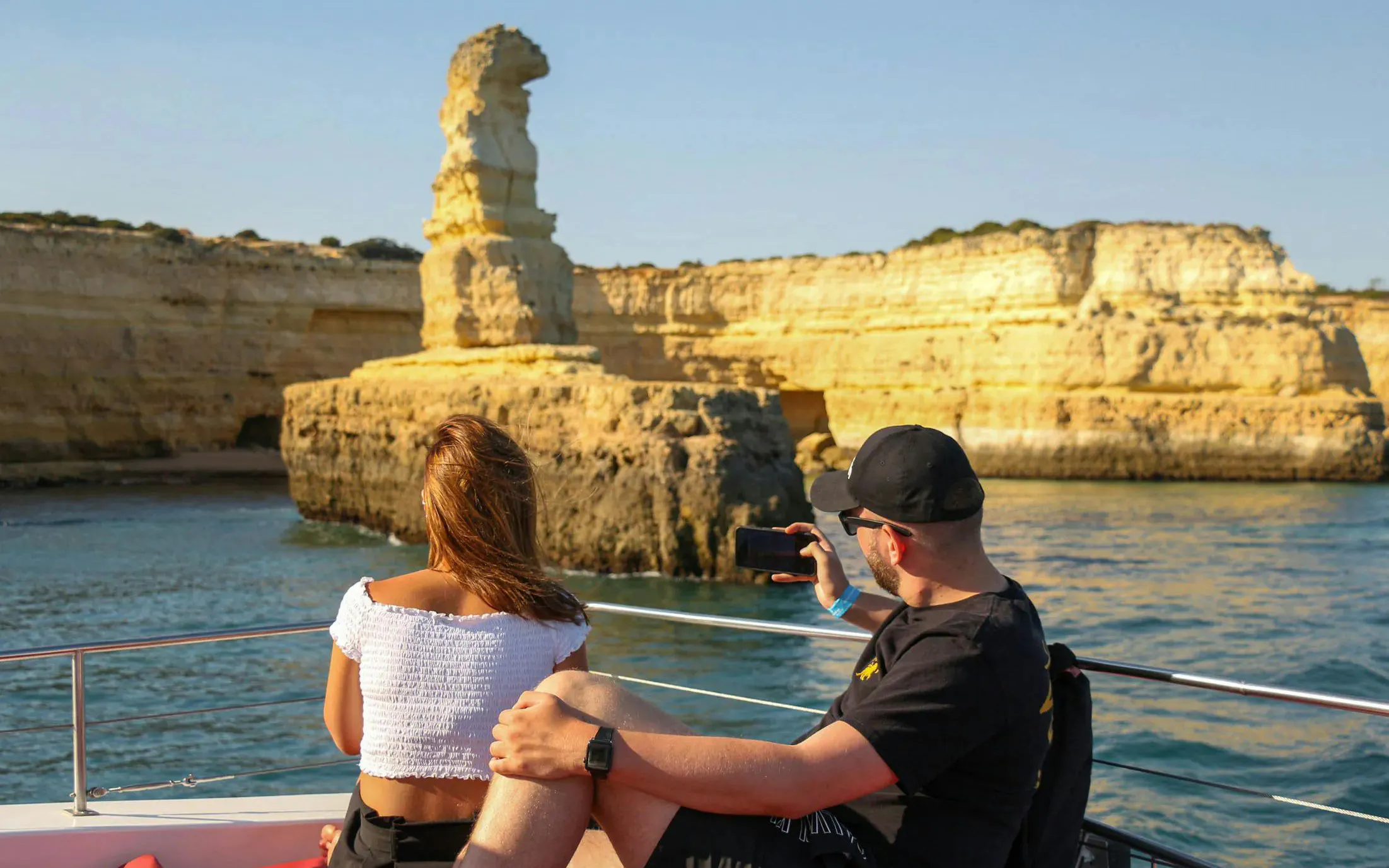 Tourists on a boat viewing rock formations during Algarve sunset sailing tour from Vilamoura.