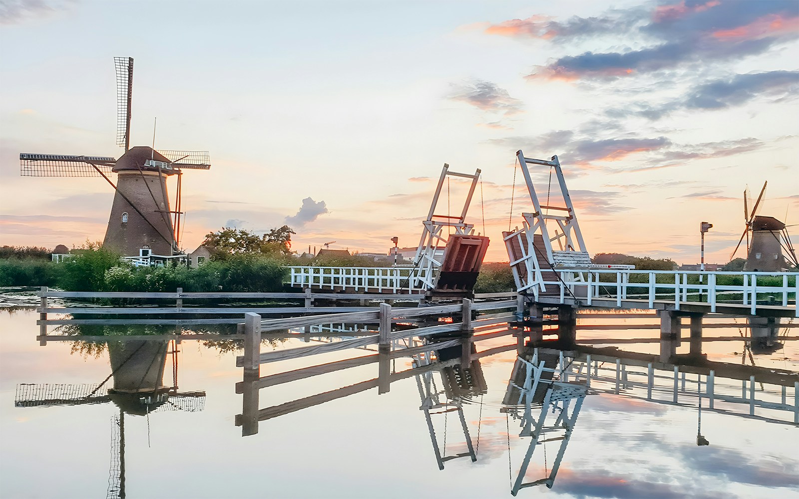 Windmills and drawbridge at sunset in Kinderdijk, Netherlands, UNESCO World Heritage site.