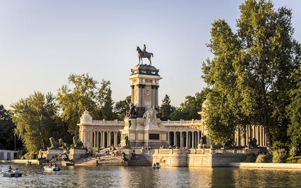 Monument to Alfonso XII with boats on the lake in El Retiro Park, Madrid.