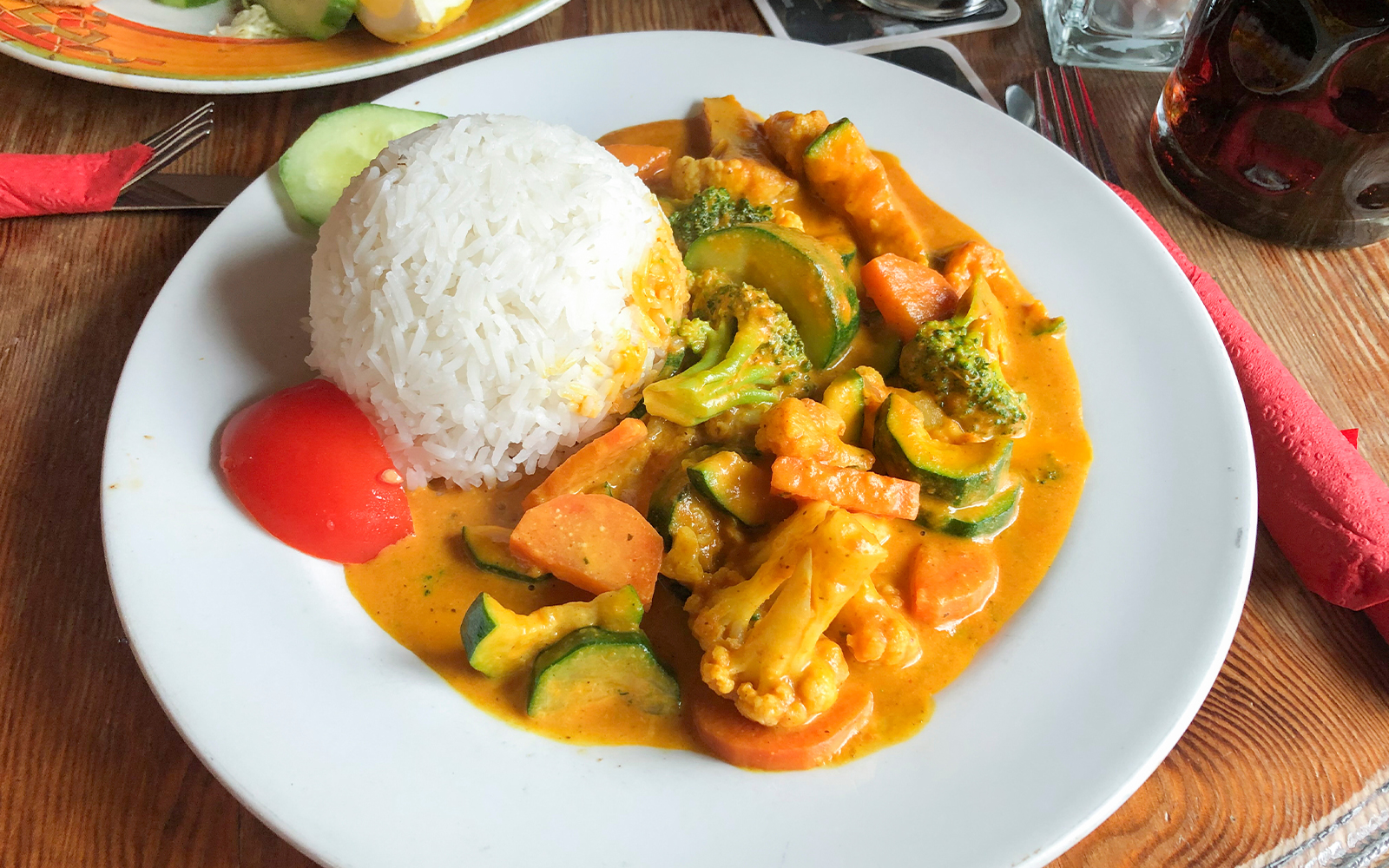 Seafood rice dish with vegetables and curry sauce on a white plate.