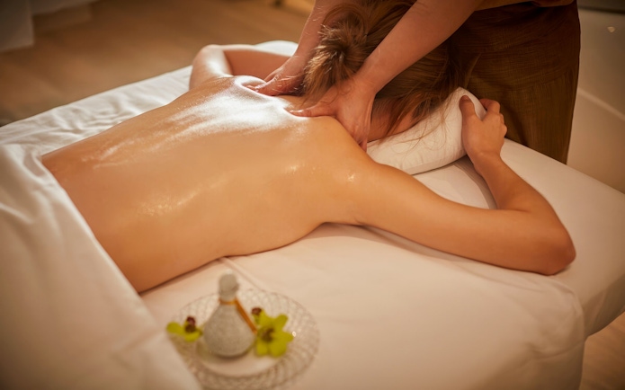 Person receiving a Diora Signature Body Scrub massage on a spa table.