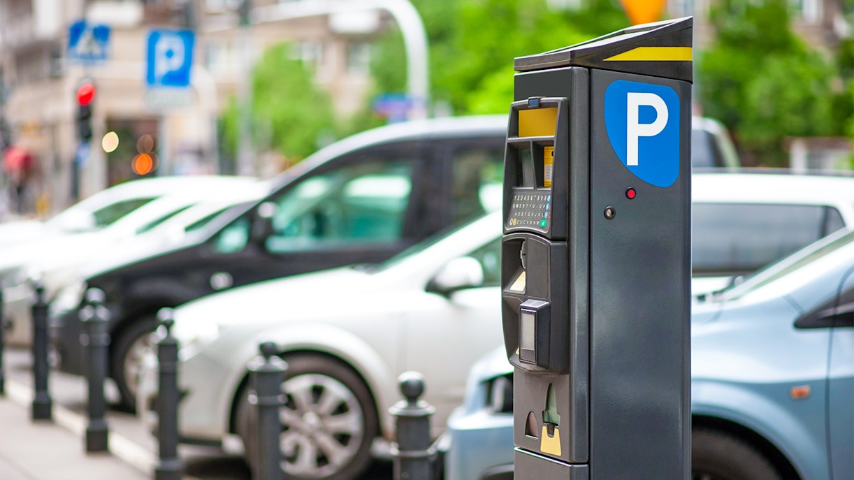 Parking meter near Lello Library, Porto, with cars in the background.