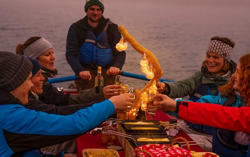 Group enjoying raclette dinner on a raft during river rafting tour in Interlaken.