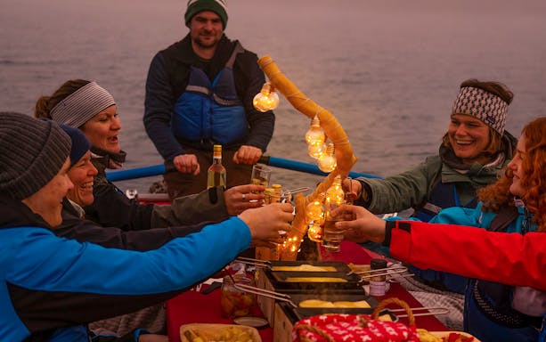 Group enjoying raclette dinner on a raft during river rafting tour in Interlaken.