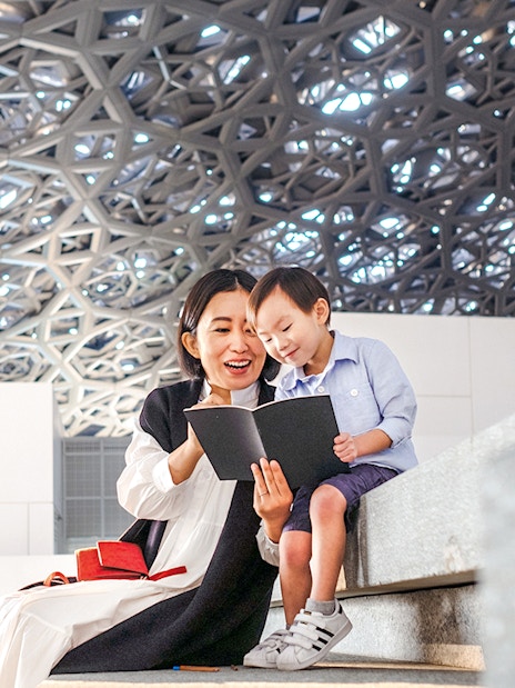 Guests reading a book under the dome at Louvre Museum Abu Dhabi.