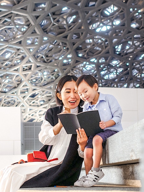 Guests reading a book under the dome at Louvre Museum Abu Dhabi.