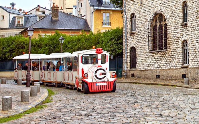 Montmartrain carrying tourists on cobblestone street in Montmartre, Paris.