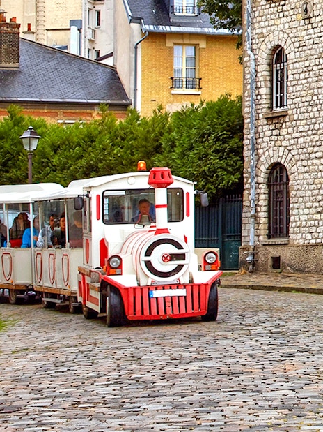 Montmartrain carrying tourists on cobblestone street in Montmartre, Paris.