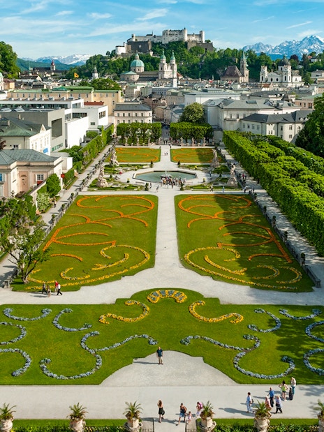 Mirabell Garden in Salzburg with geometric flower beds and view of Hohensalzburg Fortress.
