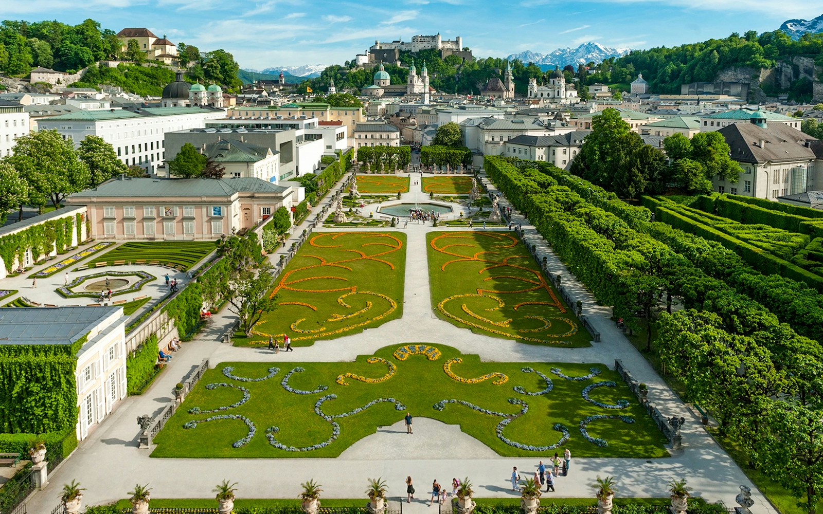 Mirabell Garden in Salzburg with geometric flower beds and view of Hohensalzburg Fortress.