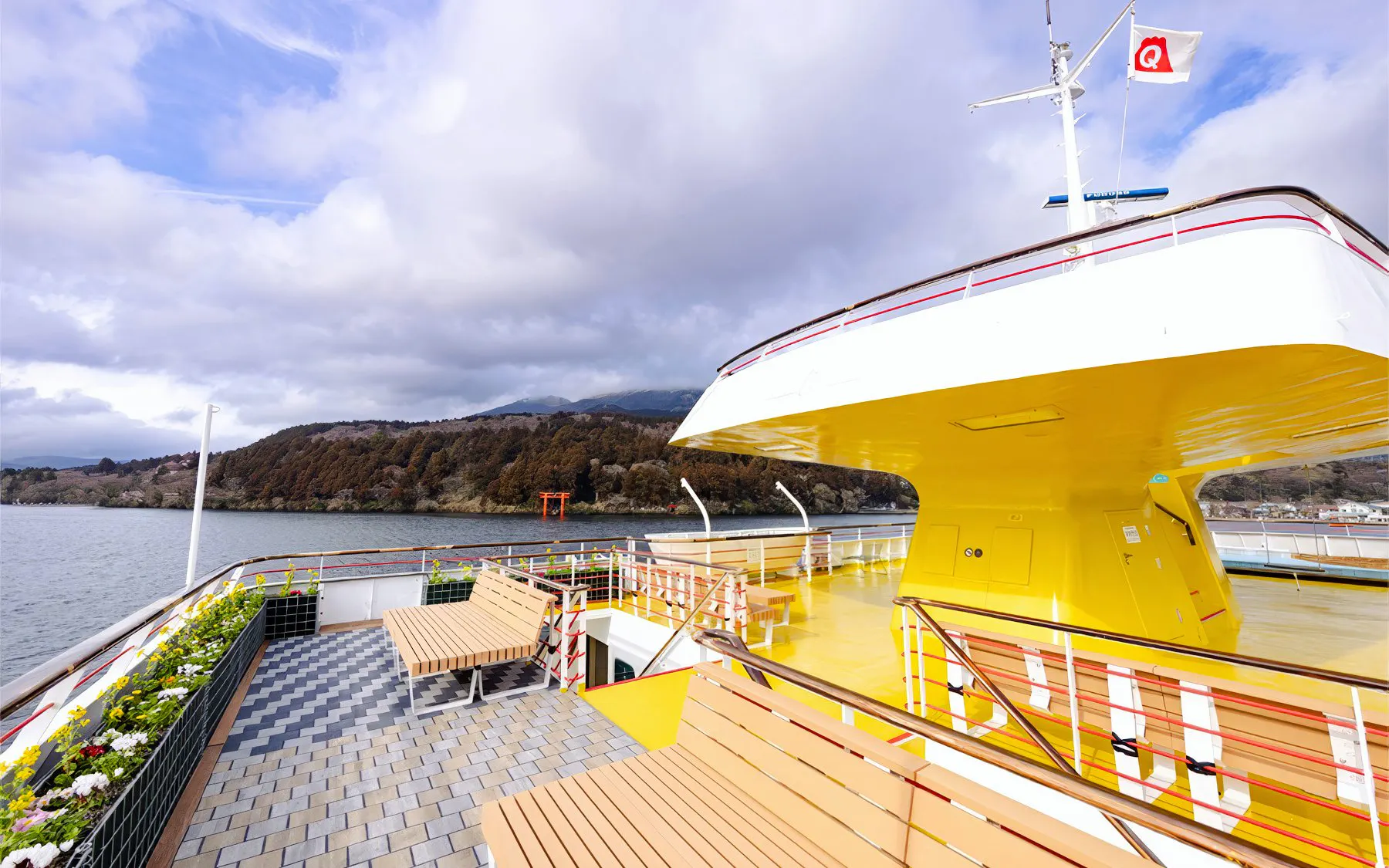 Deck view from Hakone Sightseeing Cruise with torii gate and mountains in the background.