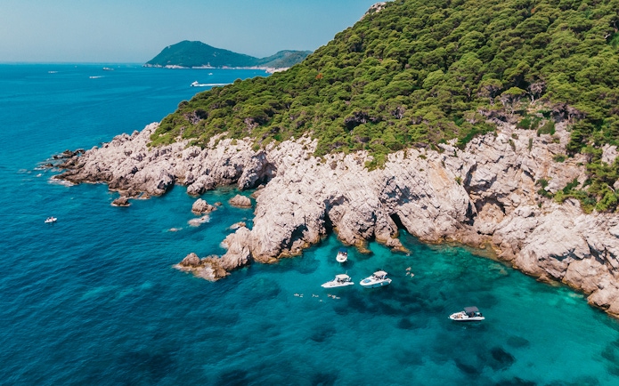 Private boats near rocky coastline and caves, Elaphiti Islands, Dubrovnik.